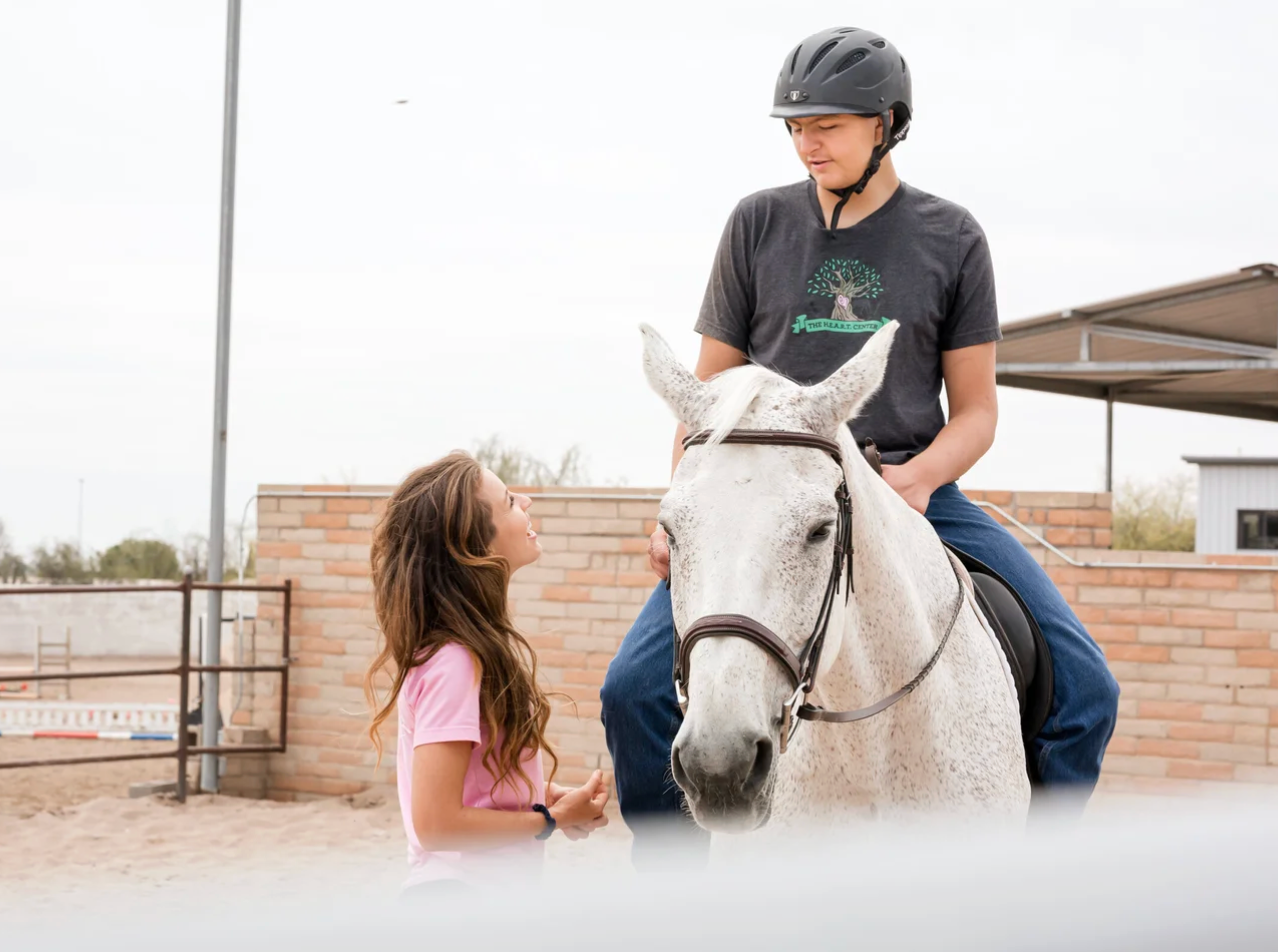 Student riding a horse with an instructor